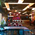 Interior of a modern bar with vibrant lighting, geometric patterns on the floor, and stylish furniture.