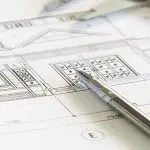 Architectural blueprints with a mechanical pencil resting on top, indicating planning or design work.