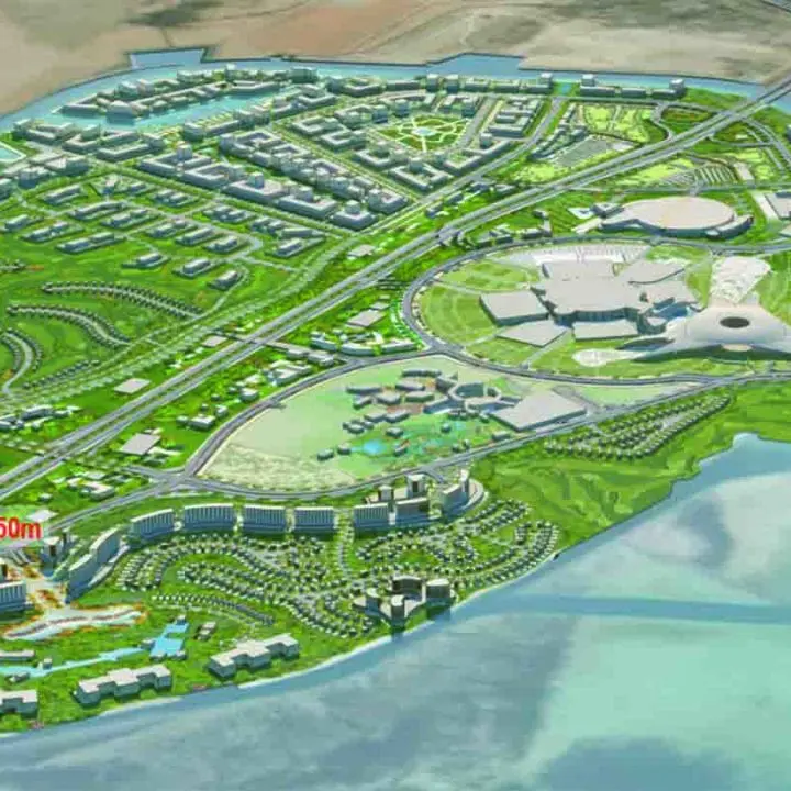 An aerial illustration of a modern coastal development plan, featuring residential areas, green spaces, and commercial buildings, with a labeled distance indicator for scale.