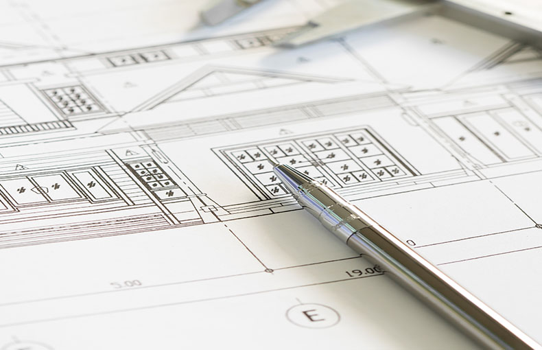 Architectural blueprints with a mechanical pencil resting on top, indicating planning or design work.
